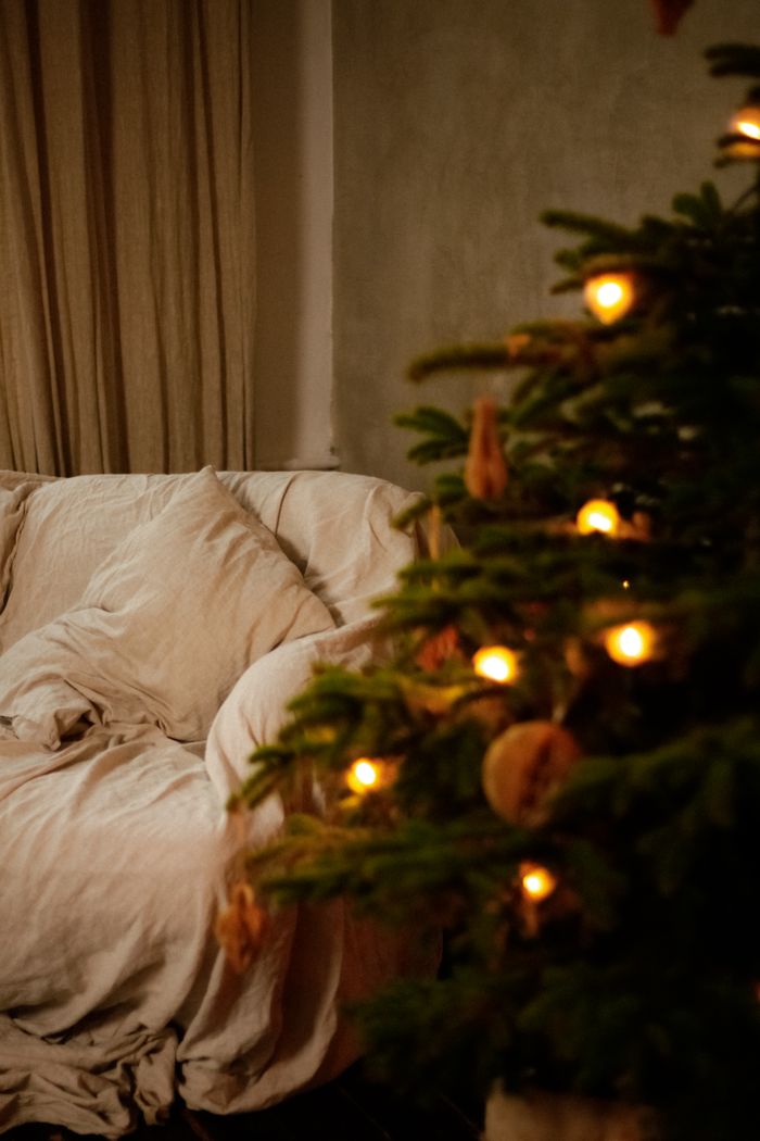 Warm and cozy living room corner decorated with a Christmas tree and glowing lights.